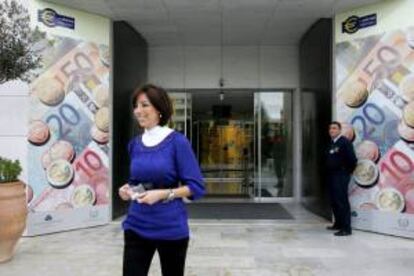 Una mujer camina entre dos vallas publicitarias con monedas y billetes de euro. EFE/Archivo