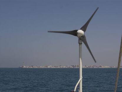 Imagen del pequeño aerogenerador del barco de la organización Oceana, fondeado el pasado miércoles a dos millas de Chipiona. Al fondo, el municipio gaditano.
