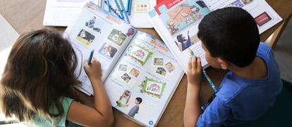 Dos niños con libros de texto de primaria.