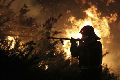 Un bombero lucha contra el incendio forestal declarado en la localidad de Fornelos de Montes, que ha provocado la muerte de dos agentes antiincendos y el desalojo de viviendas próximas.