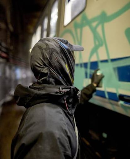 Manoteras, Madrid. A graffiti artist fills the letters with his name, using an aerosol can.