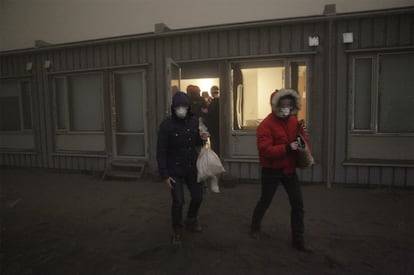 Varios turistas en la localidad de Nupur abandonan su hotel protegidos contra la nube de ceniza arrojada por el volcán Grimsvoetn.