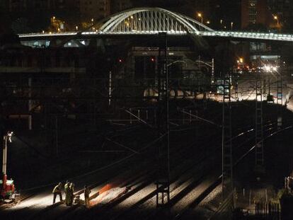 Un grupo de operarios coloca raíles en las proximidades de la futura estación, con el puente de Bac de Roda al fondo.