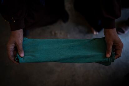 Una mujer refugiada muestra una camiseta verde de un bebé doblada para ser utilizada como compresa durante su próxima menstruación.