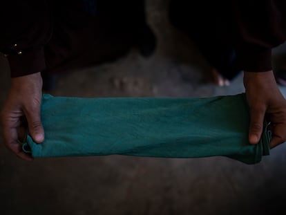 Una mujer refugiada muestra una camiseta verde de un bebé doblada para ser utilizada como compresa durante su próxima menstruación.