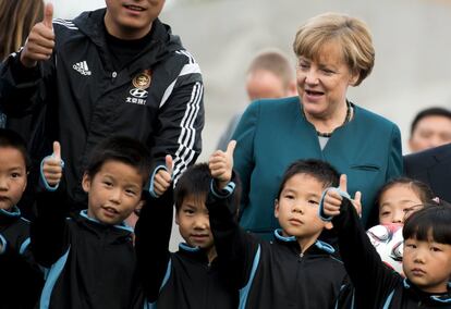 La canciller alemana, Angela Merkel, bromea con un grupo de niños en la escuela deportiva de Xinnacun Jinputao, en Hefei Baohe (China).