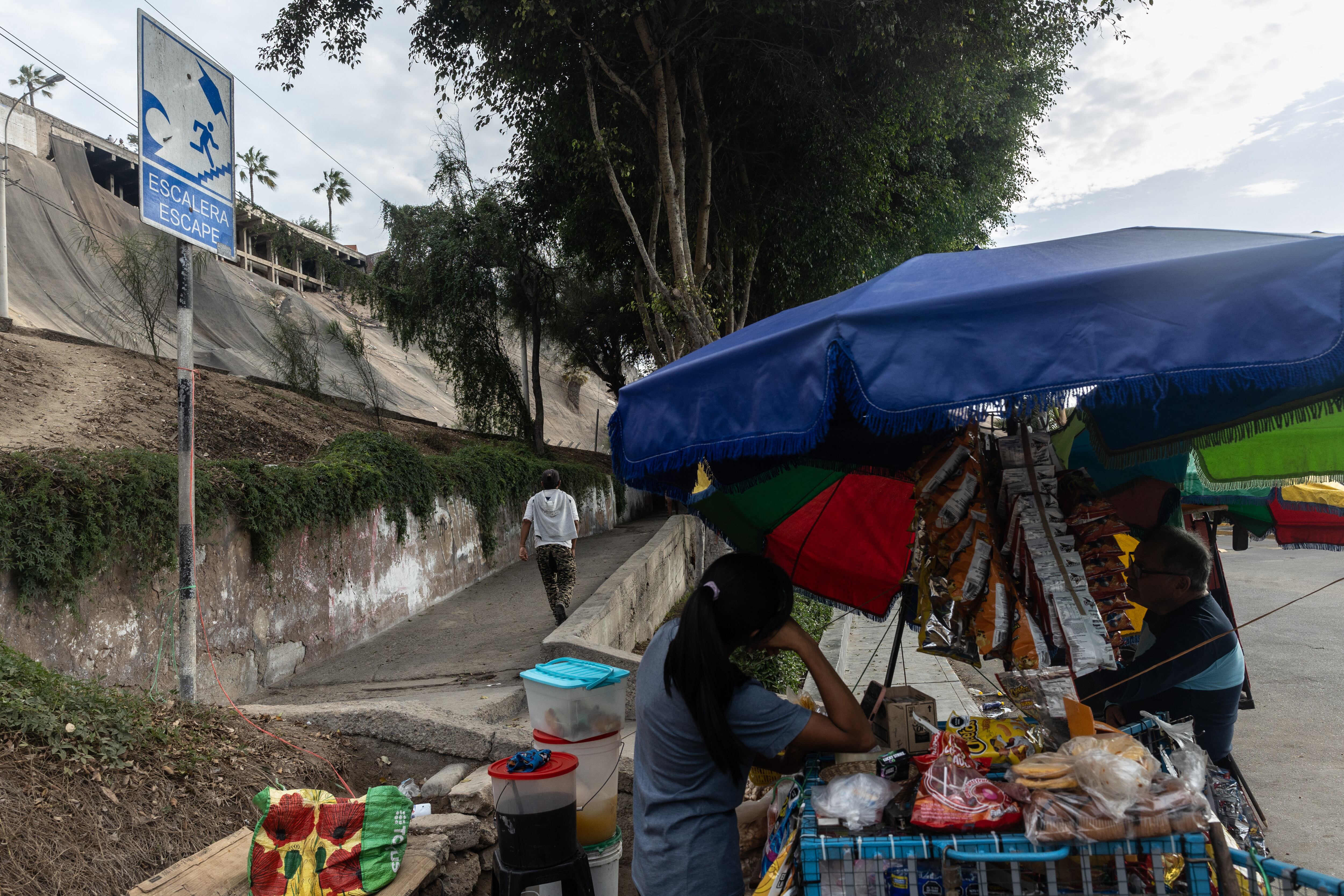 Una vendedora ambulante y un andador designado como ruta de escape, frente al muelle de la playa Pescadores, en Chorrillos.