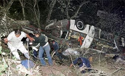 Los equipos de rescate ayudan a salir a algunos pasajeros supervivientes del autobús accidentado. PLANO GENERAL - ESCENA