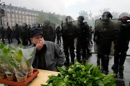 Un hombre en su puesto de flores ante la policía francesa en París, durante la manifestación del Primero de Mayo. 