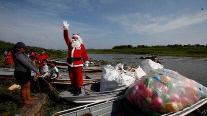 Un hombre vestido de Papá Noel saluda a los habitantes de Iranduba antes de regalar juguetes a los niños de este pueblo de la Amazonía brasileña.