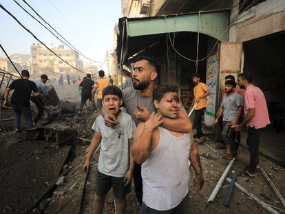 Dos niños palestinos heridos lloraban el pasado 25 de octubre mientras otros buscaban víctimas en el lugar de un ataque israelí contra un edificio residencial en Ciudad de Gaza.