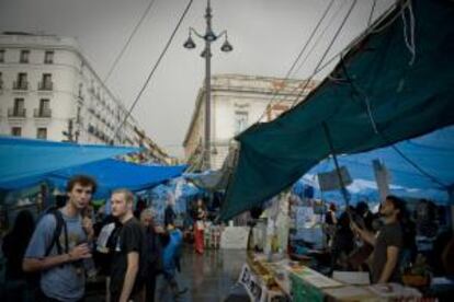 Varios turistas visitan la acampada que desde hace veinte días ocupa de céntrica plaza de la Puerta del Sol de Madrid.