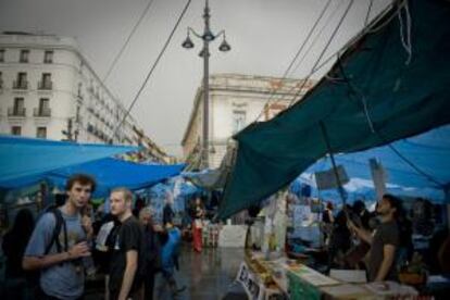 Varios turistas visitan la acampada que desde hace veinte días ocupa de céntrica plaza de la Puerta del Sol de Madrid. 