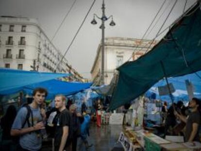 Varios turistas visitan la acampada que desde hace veinte días ocupa de céntrica plaza de la Puerta del Sol de Madrid. 