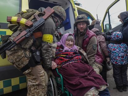 Dos soldados ucranios ayudan a evacuar a una mujer de Irpin, en las cercanías de Kiev.
