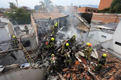 Bomberos trabajan en las casas donde se estrelló la avioneta en Medellín.