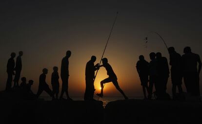 Un niño palestino salta por encima de una roca durante el atardecer en la playa de la ciudad de Gaza (Palestina), 3 mayo de 2013.