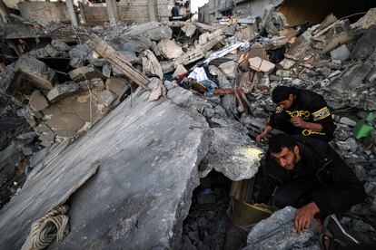 Un grupo de personas busca supervivientes entre una montaña de escombros en el edificio derruido donde la pasada noche falleció el periodista palestino Adel Zorob tras un bombardeo israelí, en Rafah, al sur de la Franja de Gaza.