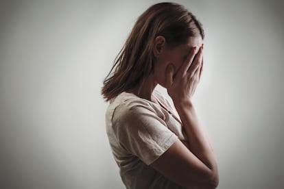 Portrait of depressed woman, covering face with her hands, side view