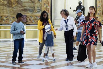 Una auxiliar de sala en el Palacio Real, rodeada de varios turistas. 