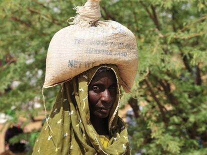 Una mujer acarrea un saco de comida distribuidos en una aldea de Burkina Faso. 