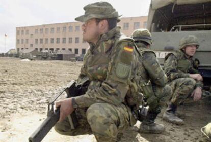 Soldados españoles desplazados a Afganistán en una expedición de 2002 se protegen tras un camión.