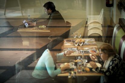Un hombre come mientras trabaja con su tableta en un restaurante.
