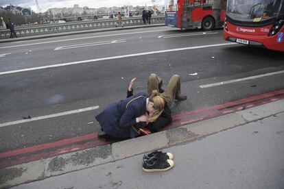 Una mujer asiste a una persona herida que yace en el suelo en el puente de Westminster en Londres.