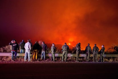 Equipos de policías y bomberos observan mientras el fuego de Thomas quema una ladera en Ojai, California.
