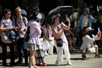 Un grupo de turistas se protege del sol mientras toman fotos, este viernes.