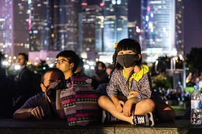 Una niña viste una máscara facial en el recuerdo a un joven fallecido en las protestas de Hong Kong.