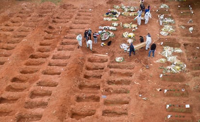 Los trabajadores del cementerio entierran a tres víctimas de coronavirus en el cementerio de Vila Formosa, en Sao Paulo, Brasil.