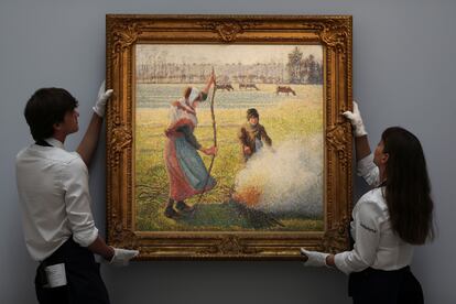 Dos empleados de Sotheby's sujetan el cuadro 'Gelee Blanche, Jeune Paysanne enciende un fuego' , de Camille Pissarro.