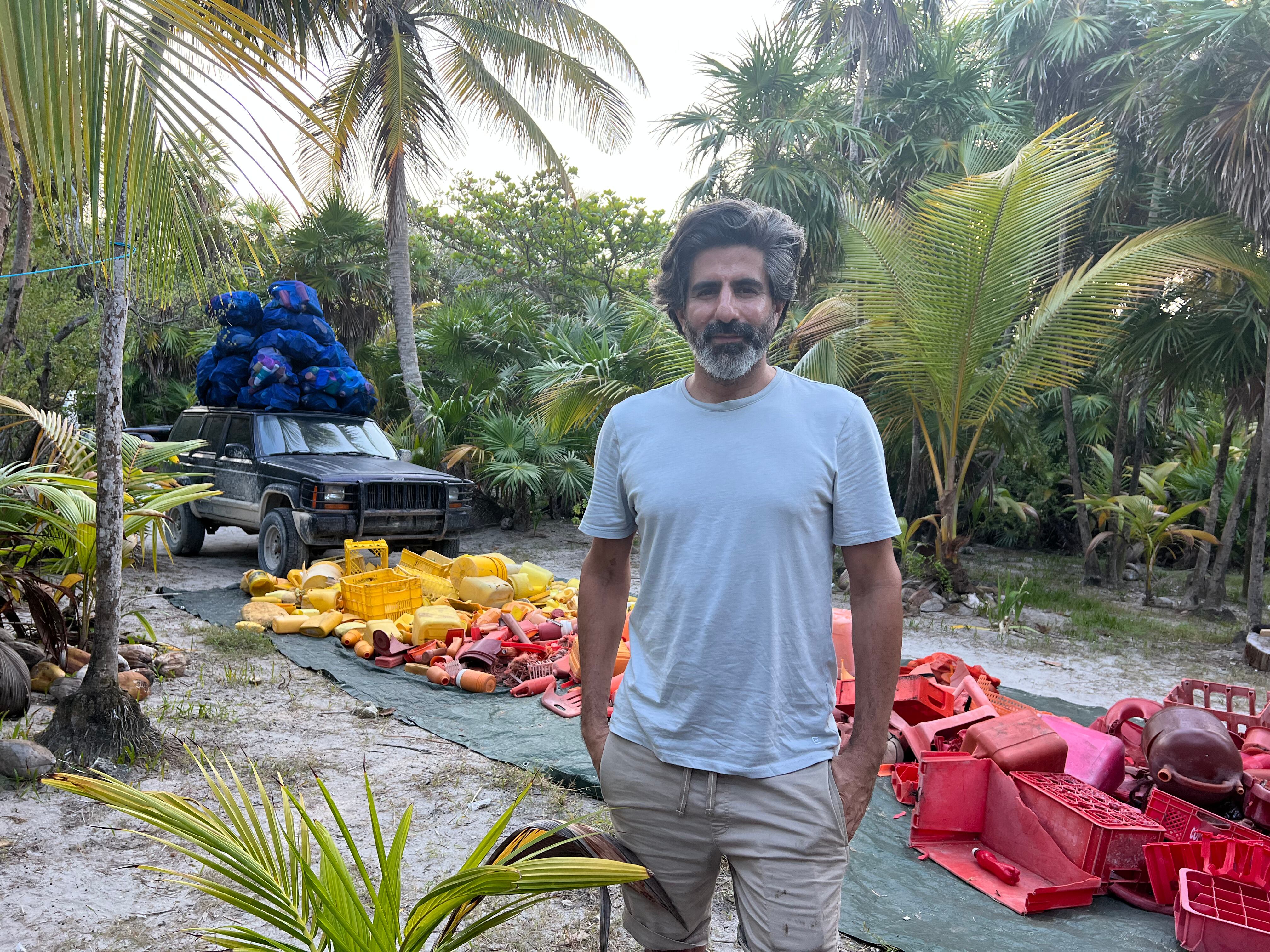 Alejandro Durán posa para un retrato junto a pilas de basura recolectadas de las playas de Tulum.
