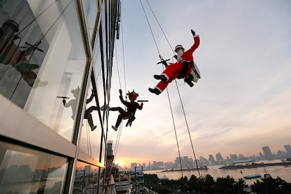 Un operario vestido de Papá Noel se descuelga para limpiar los cristales de un edificio en Tokio (Japón), el 21 de diciembre de 2016.