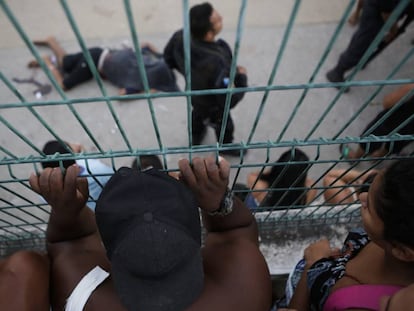 Pessoas olham para o corpo de um dos homens executados pela polícia do Rio, nesta sexta-feira.