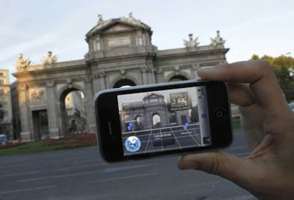 Un turista utiliza su iPhone para situarse en la puerta de Alcalá de Madrid.