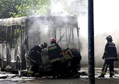 Los bomberos sofocan las llamas que han calcinado el autobús urbano.