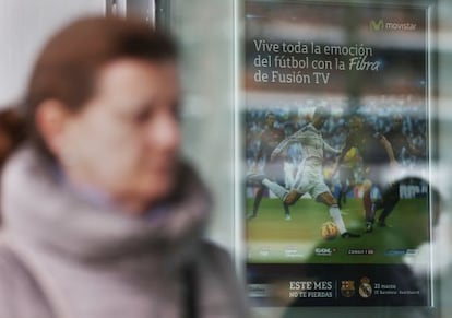 Una mujer pasa frente a un anuncio de Fusión TV en una tienda de Telefónica Movistar.