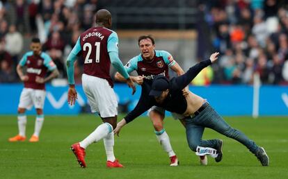 El capitán del West Ham Mark Noble se enfrenta a un aficionado que saltó a la cancha.
