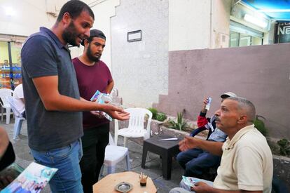 Amen Alá Jawhary intentando convencer a un anciano de que le vote en un café de Manuba.