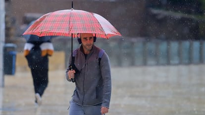 Un joven se protege de la lluvia en una calle de Málaga, el 14 de marzo.