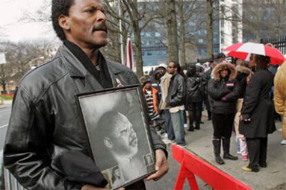 Un hombre muestra una foto de Martin Luther King ante la cola del funeral de Coretta King en Atlanta.