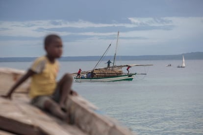 Varias personas transportan madera en una embarcación frente a la costa de Paquitequete, en Mozambique.