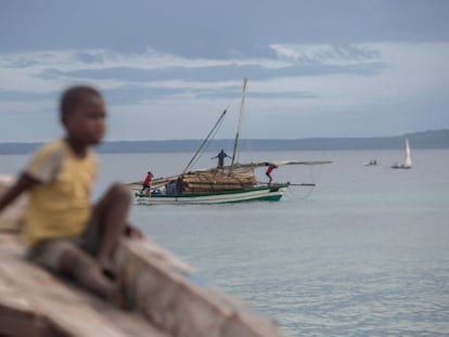 Varias personas transportan madera en una embarcación frente a la costa de Paquitequete, en Mozambique.