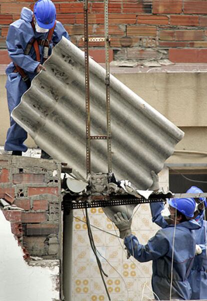 Tres operarios trabajan en el derribo manual de uno de los edificios.