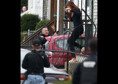 Una mujer sale de su casa protegida por la polic&iacute;a en la zona donde los cuerpos de seguridad trabajan en la b&uacute;squeda de un sospechoso de los atentados  del marat&oacute;n de Boston. 