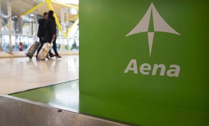 Dos viajeros pasan ante un cartel de Aena en el aeropuerto de Barajas.