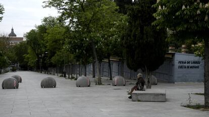 Una mujer espera sentada en un banco de la Cuesta de Moyano (Madrid).