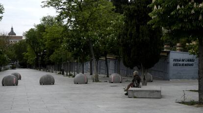 Una mujer espera sentada en un banco de la Cuesta de Moyano (Madrid). 